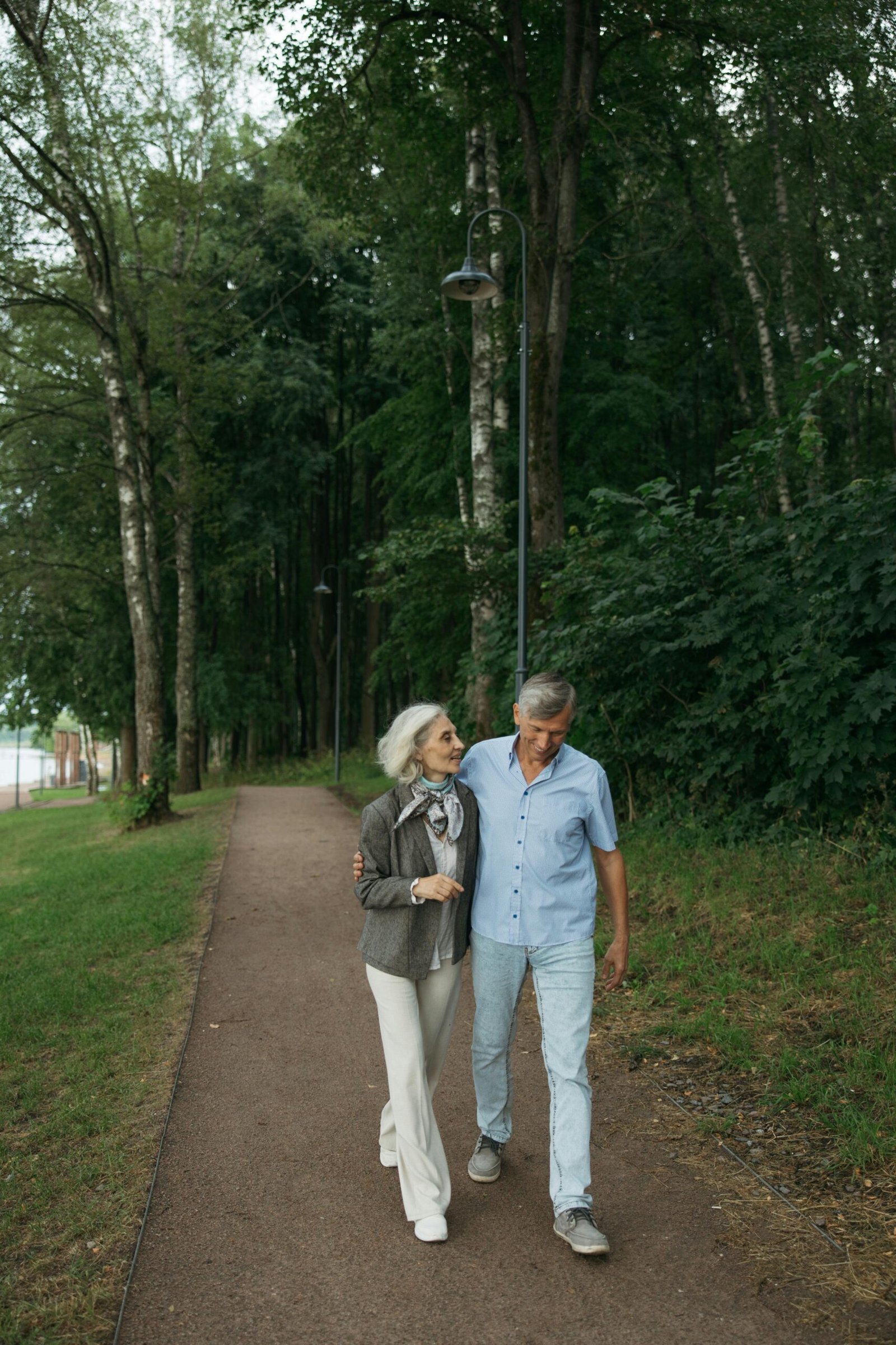 Elderly couple strolling on a forest path, enjoying nature together.